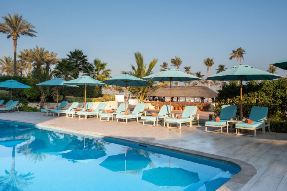 JA Beach Hotel Dubai swimming pool with sun loungers and palm trees